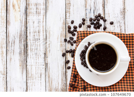 Coffee cup and coffee beans on white wooden table Coffee cup and coffee beans on white wooden table 107649670
