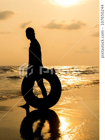 silhouette of young woman walking on beach 107650244