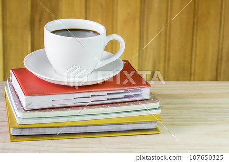 Cup of coffee and book on wooden table 107650325
