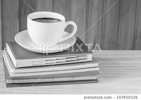 Cup of coffee and book on wooden table 107650326