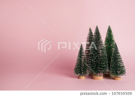 Christmas trees on pastel pink background. Minimal holiday concept. New year simple composition. Merry Christmas and happy New Year greeting card Christmas trees on pastel pink background. Minimal holiday concept. New year simple composition. Merry Christmas and happy New Year greeting card 107650509