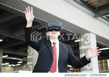 Young businessman using VR in warehouse Young businessman using VR in warehouse 107650940