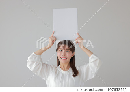 Business woman holding a message board vertically above her head 1 Business woman holding a message board vertically above her head 1 107652511