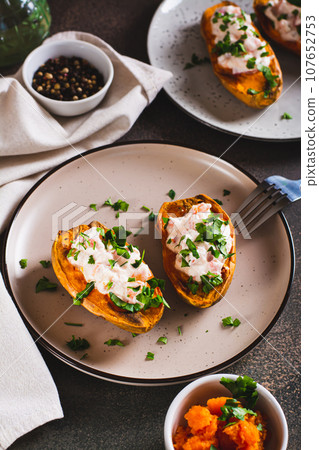 Baked sweet potato filled with ricotta, tomato and parsley on a plate vertical view Baked sweet potato filled with ricotta, tomato and parsley on a plate vertical view 107652753