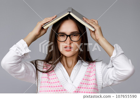 with book on head on grey background 107655590