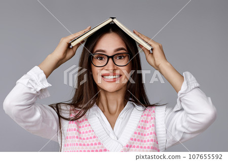 woman with book on head on grey background woman with book on head on grey background 107655592