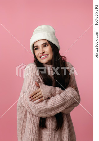 woman in hat, sweater hugging herself and smiling feeling happ 107655593