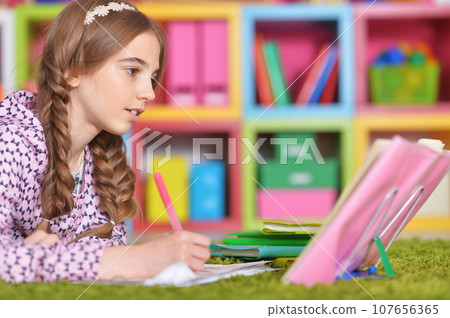 Portrait of little girl drawing with pencil in her room 107656365