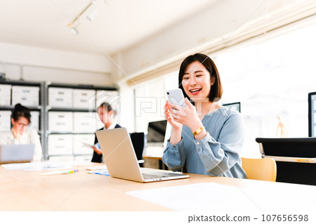 一名女性在工作中使用智慧型手機 一名女性在工作中使用智慧型手機 107656598
