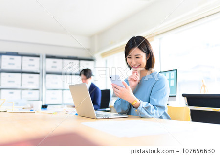 A woman operating a smartphone at work 107656630