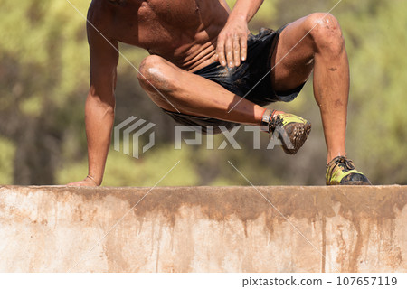 Mud race runners running over obstacles extreme sport Mud race runners running over obstacles extreme sport 107657119
