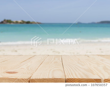 wooden table in front of abstract blurred in view of the beach and sky background 107658357