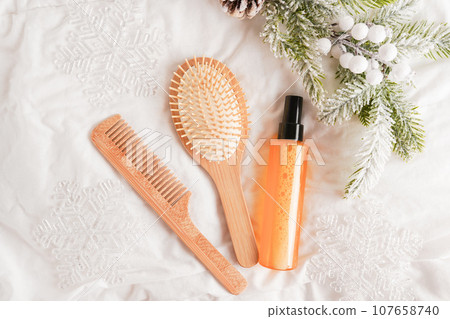 Essential oil and wooden hairbrushes with Christmas fir branch on white bed background 107658740