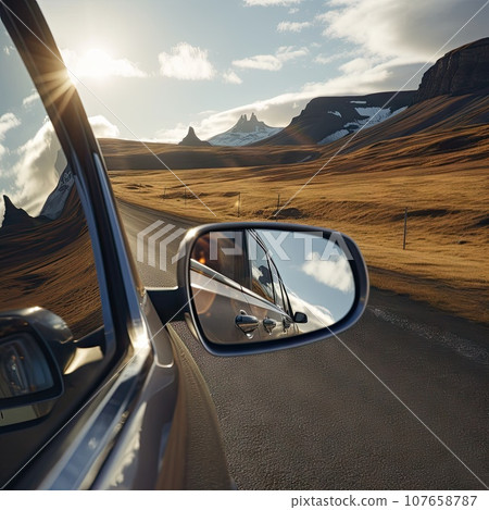 the side view mirror of a car as it drives down a mountain road with snow capped mountains in the background the side view mirror of a car as it drives down a mountain road with snow capped mountains in the background 107658787