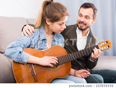 Guitar tutor helping client learn instrument Guitar tutor helping client learn instrument 107659339