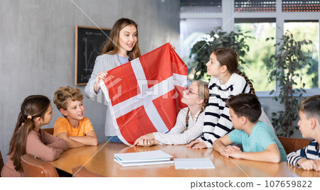 Teacher showing Denmark flag to group of preteen schoolchildren Teacher showing Denmark flag to group of preteen schoolchildren 107659822