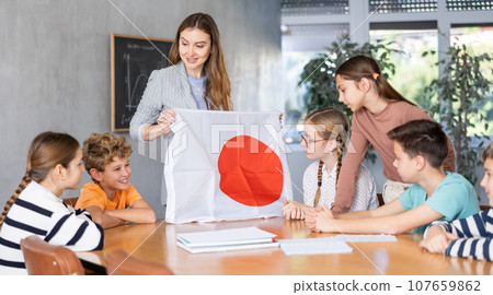 Teacher showing Japan flag to group of schoolchildren Teacher showing Japan flag to group of schoolchildren 107659862