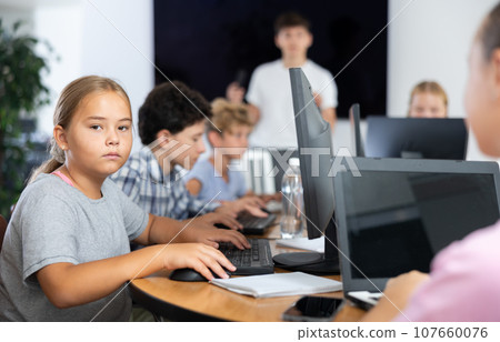 Preteen girl working with computer programs in training room Preteen girl working with computer programs in training room 107660076