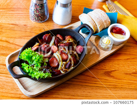 Fried sausages on onions Fried sausages on onions 107660175