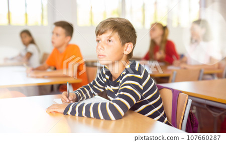 Smart boy writing during class in school Smart boy writing during class in school 107660287