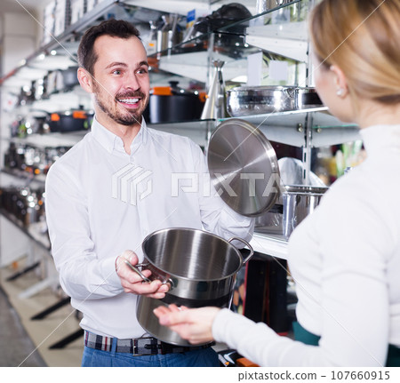 Male seller demonstrating saucepans 107660915