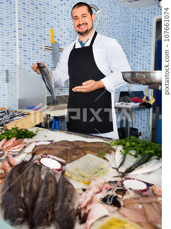 Seller behind scales and fish counter showing fish 107661074
