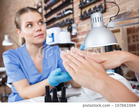 Manicurist girl polishing nails to female client in salon 107661094