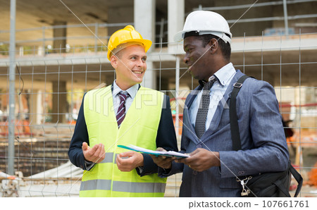 Portrait of an engineer and architect with folder of documents at construction site 107661761