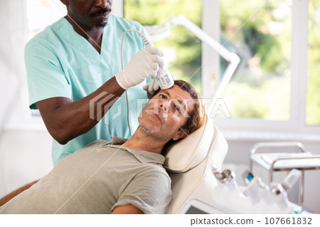 Man client undergoes facial skin care procedure using nozzle cold hammer whitening 107661832