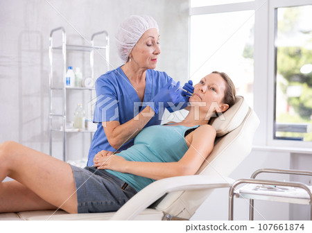 Woman getting procedure of injection contouring and for facial correction in clinic 107661874