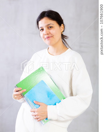 Smiling young female tutor or college student with workbooks 107661900