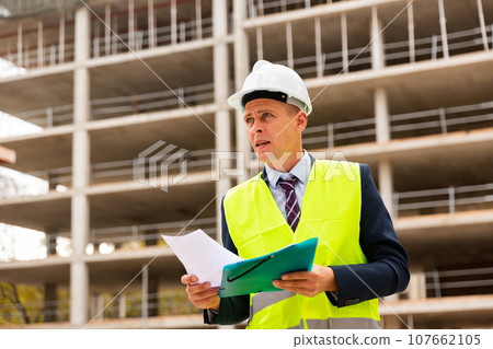 Foreman checking documentation on construction site 107662105