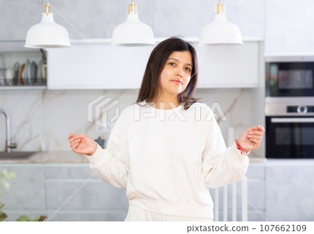 Positive confident young woman posing in home kitchen Positive confident young woman posing in home kitchen 107662109