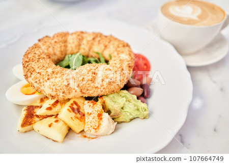 Turkish breakfast with simit, cheese, tomato, cucumber, olives. Breakfast with coffee in the restaurant. Morning nutritious meal Turkish breakfast with simit, cheese, tomato, cucumber, olives. Breakfast with coffee in the restaurant. Morning nutritious meal 107664749