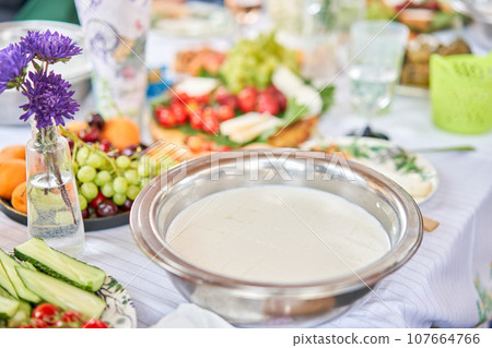 Cut with a knife, separate the serum. Master class and cheese tasting. Women make cheese. The enzyme and starter culture are added to the milk in a metal container. Milk folding process, home 107664766