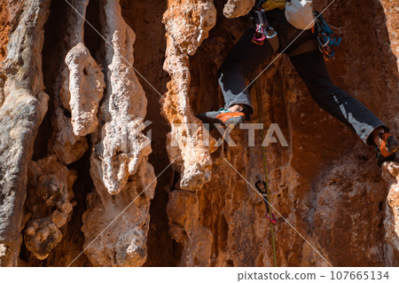 Young man is climbing on the rocks in the mountains. Young man is climbing on the rocks in the mountains. 107665134
