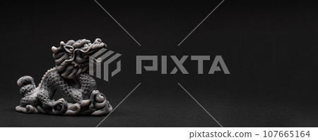 Gray dragon statue on a black background. The symbol of 2024. 107665164