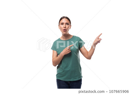 young beautiful brunette woman dressed in a green t-shirt points with her hand at copy space on a young beautiful brunette woman dressed in a green t-shirt points with her hand at copy space on a 107665906