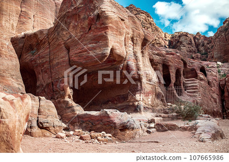 View of the Temples and caves carved into the sandstone rock in the gorge. Petra, Jordan 107665986