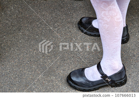 Legs of a schoolgirl in white tights and black shoes 107666013