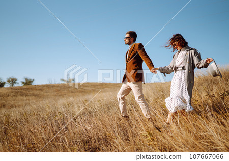 Stylish and loving couple enjoying each other outdoors. Stylish couple walking and hugging. Stylish and loving couple enjoying each other outdoors. Stylish couple walking and hugging. 107667066