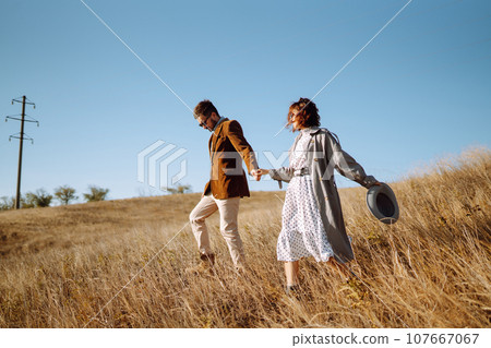 Stylish and loving couple enjoying each other outdoors. Stylish couple walking and hugging. Stylish and loving couple enjoying each other outdoors. Stylish couple walking and hugging. 107667067