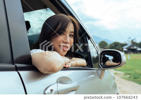 Smiling female driving vehicle on the road on a bright day. Sticking her head out the windshield 107668243