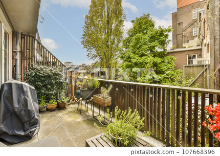 an outside area with some plants and pots on the side of a building, in front of a wooden fence 107668396