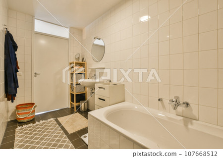 a bathroom with white tiles on the walls and black flooring around the tub, sink, mirror and toilet 107668512