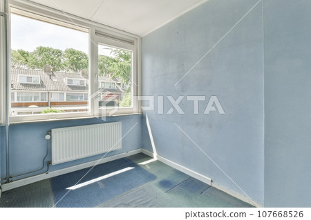 an empty room with blue walls and white trim on the window sies, in front of a view of houses an empty room with blue walls and white trim on the window sies, in front of a view of houses 107668526