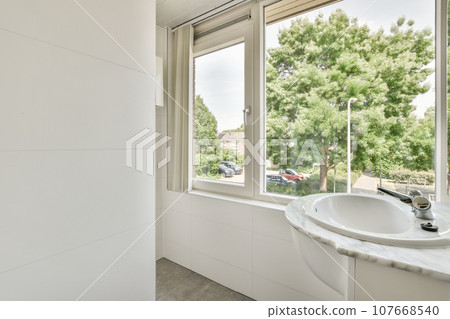 a bathroom with a sink and large window looking out at the trees outside in the photo is taken from inside a bathroom with a sink and large window looking out at the trees outside in the photo is taken from inside 107668540