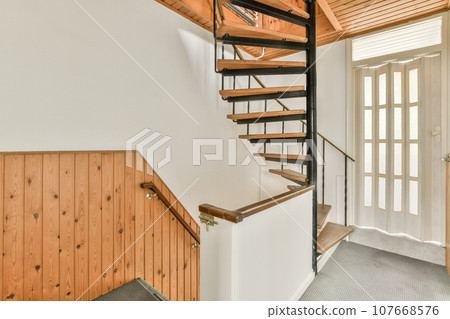 a wooden staircase in a house with white walls and wood paneled flooring there is a black metal handrail a wooden staircase in a house with white walls and wood paneled flooring there is a black metal handrail 107668576