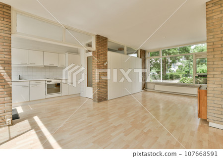 an empty living room with wood floors and white appliances in the room is well lit by the sun shining through the windows an empty living room with wood floors and white appliances in the room is well lit by the sun shining through the windows 107668591