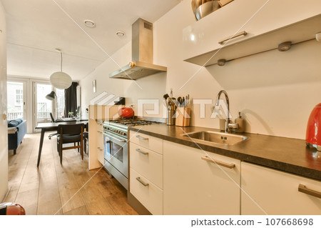 a kitchen and dining area in a house with wood floors, white cabinets and stainless steel appliances on the wall a kitchen and dining area in a house with wood floors, white cabinets and stainless steel appliances on the wall 107668698